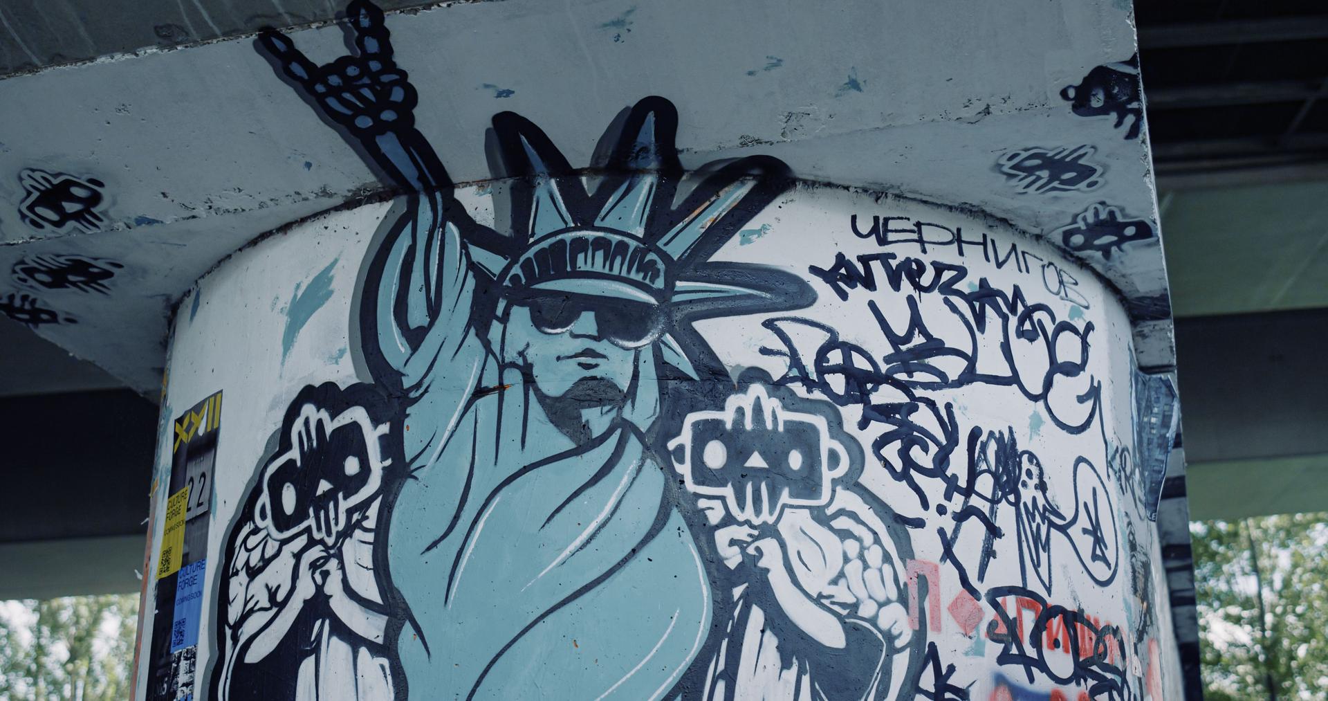 Modern drawing statue of liberty on column at skate park. Graffiti on wall.